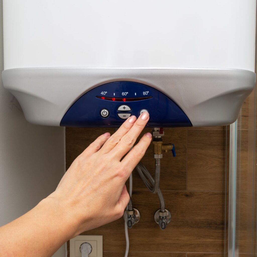 female hand reaching up to a tankless water heater to push a button
