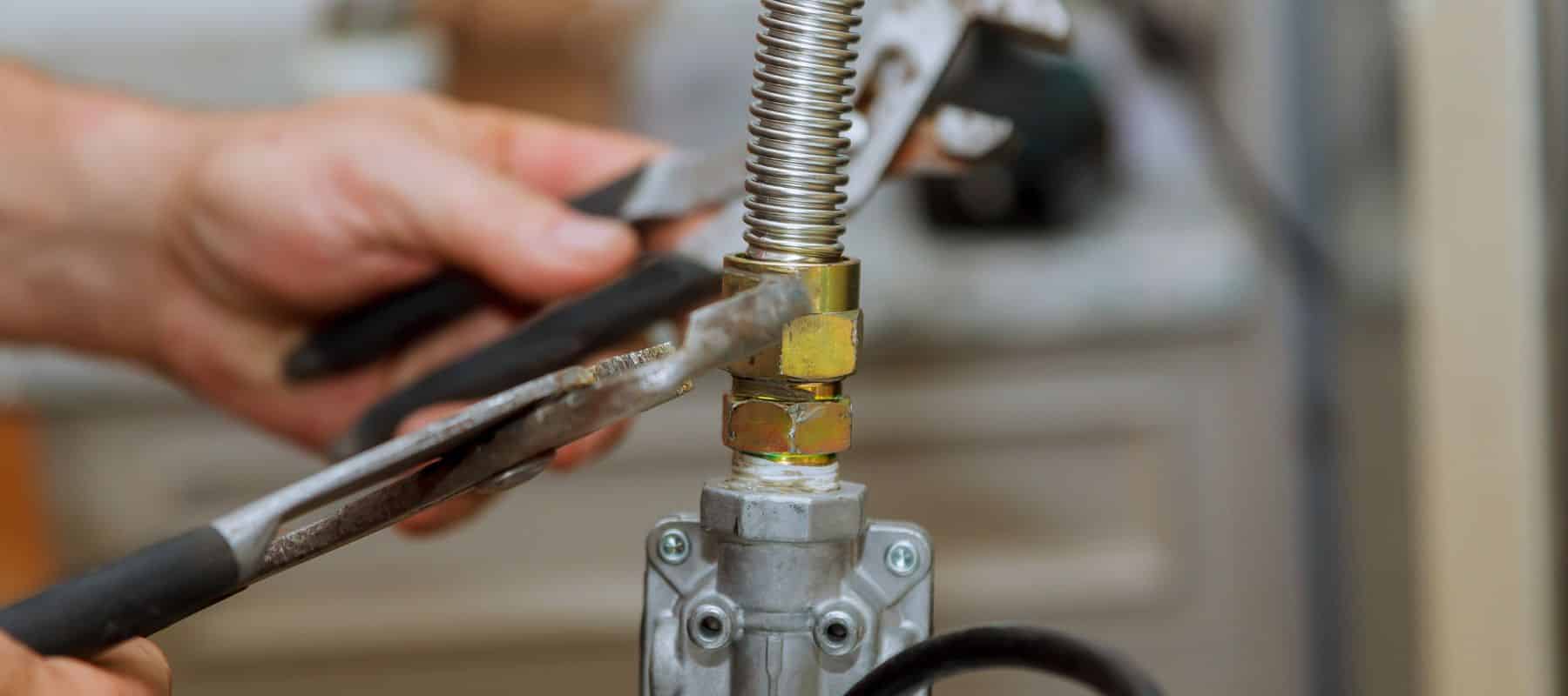 closeup of a plumber hands holding two wrenches tightening a section on plumbing pipes