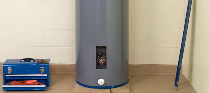 closeup of a tanked water heater with a blue tool box next to it