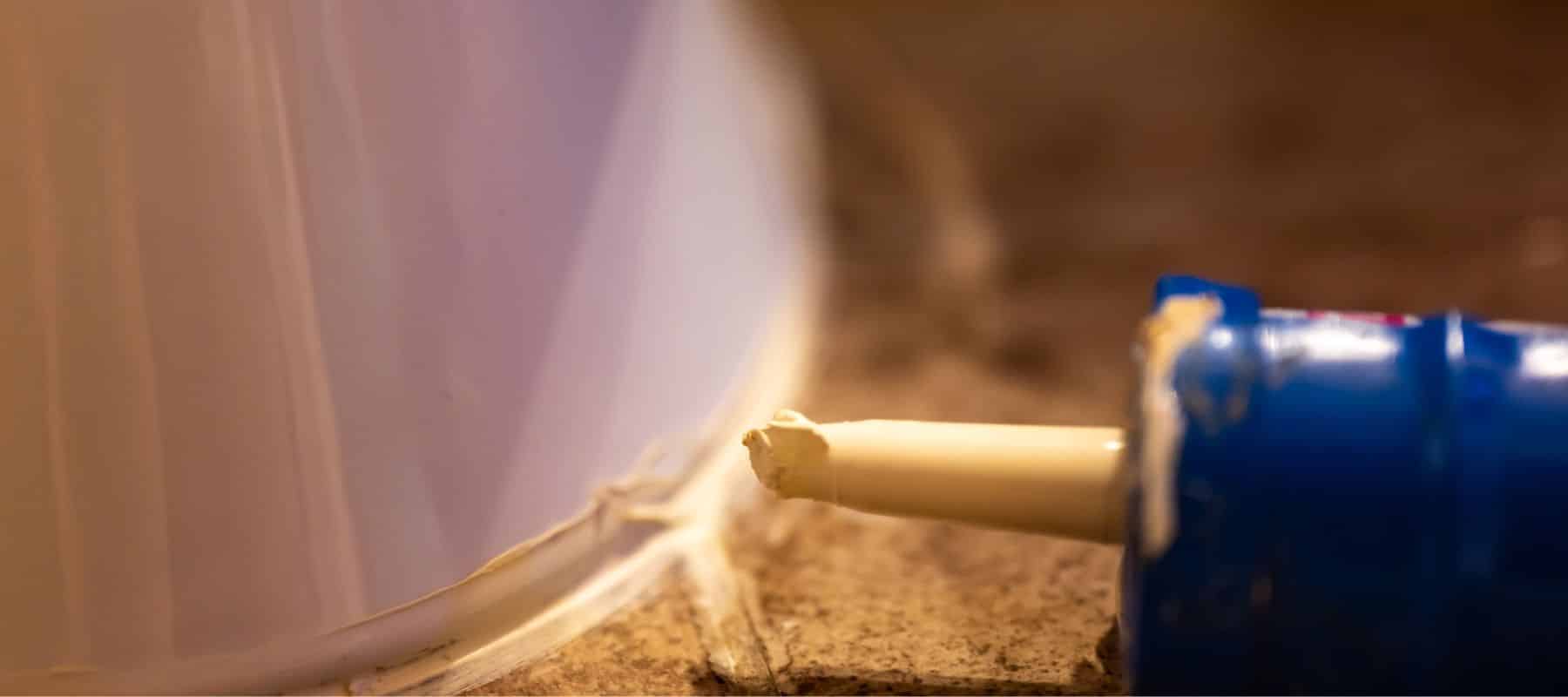 caulk being used to seal the base of a toilet