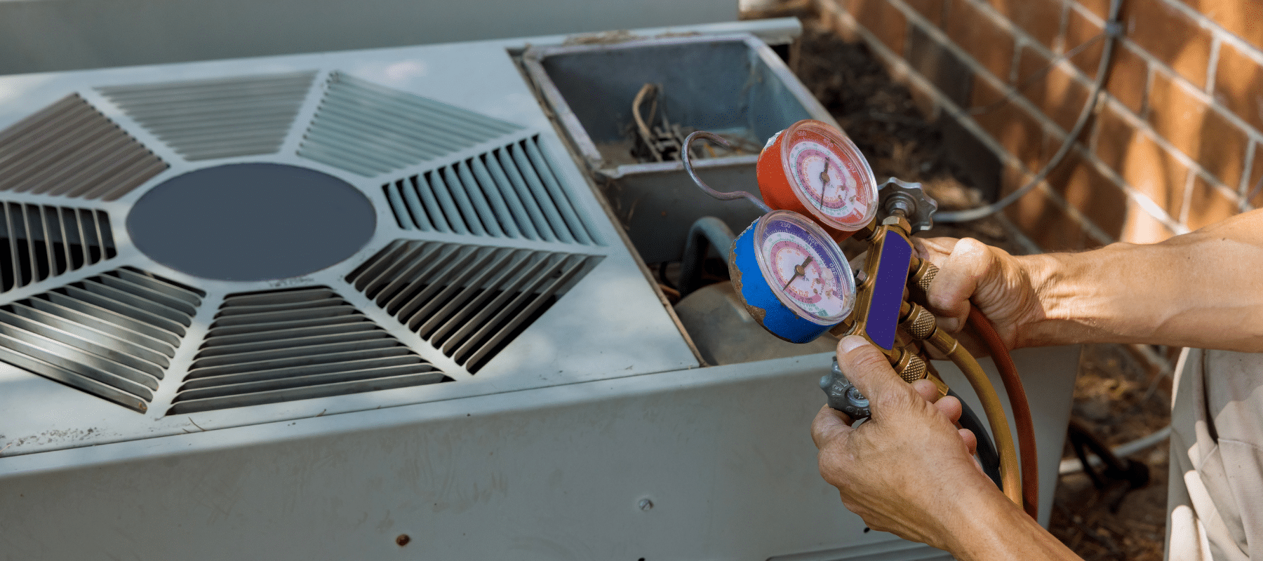 Close-up of a technician using HVAC gauges to measure pressure levels on an outdoor air conditioning unit