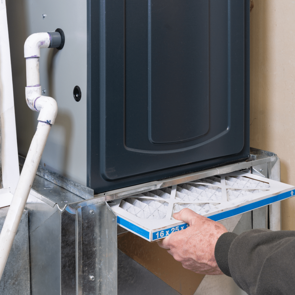 Person inserting a new air filter into an HVAC system as part of routine maintenance