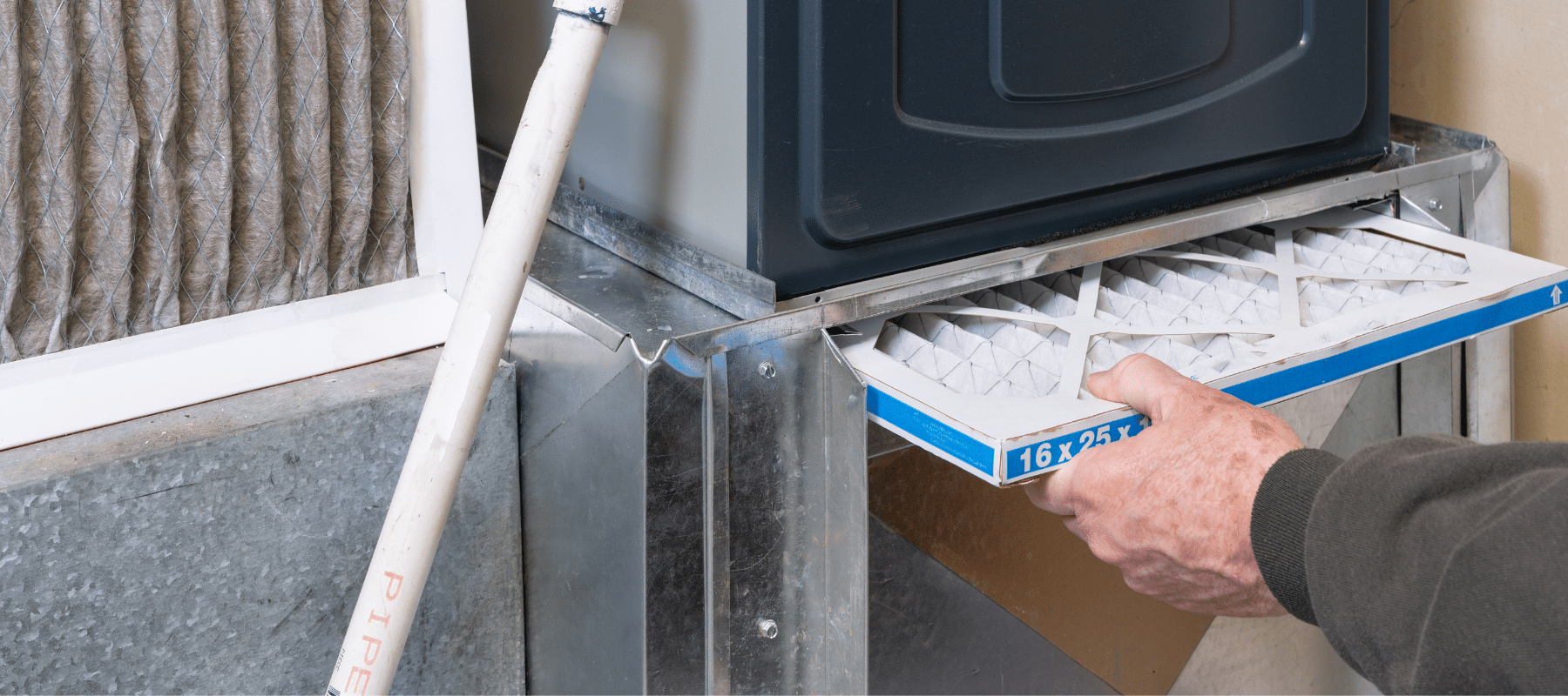 Person inserting a new air filter into an HVAC system as part of routine maintenance