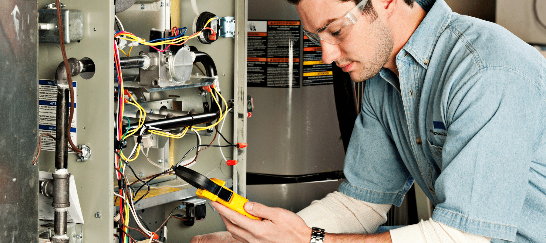 Technician using a multimeter to test wiring and connections inside an HVAC system