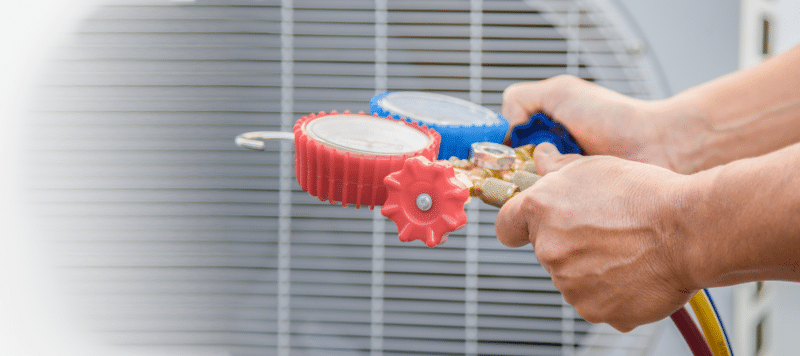 closeup of a technician using a ac refrigerant tool to measure pressure