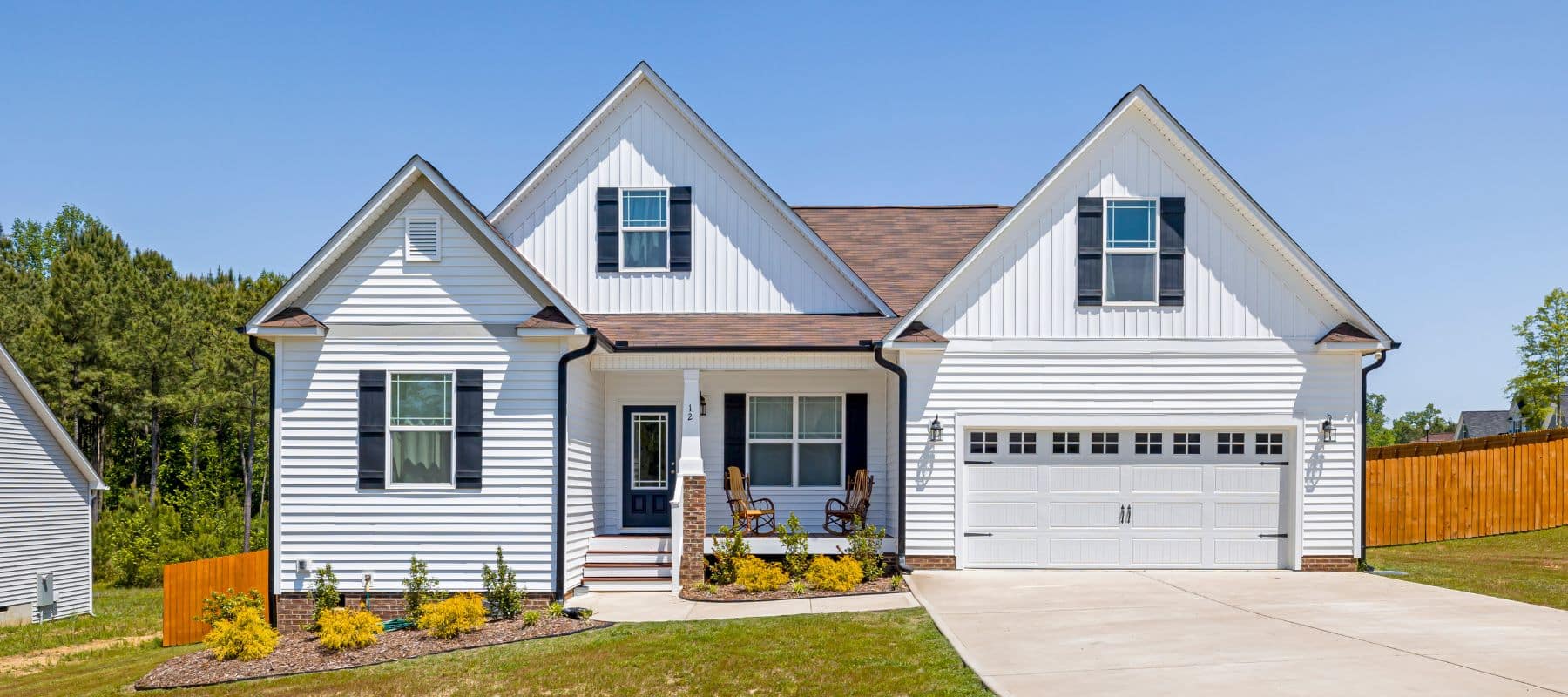 Traditional white house with gable roof, black shutters, and a welcoming front porch