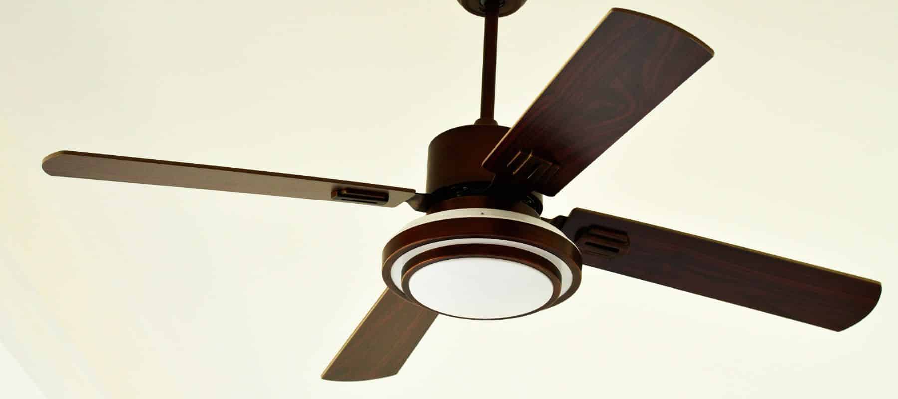 Close-up of a modern ceiling fan with wooden blades and a built-in light fixture, mounted on a white ceiling
