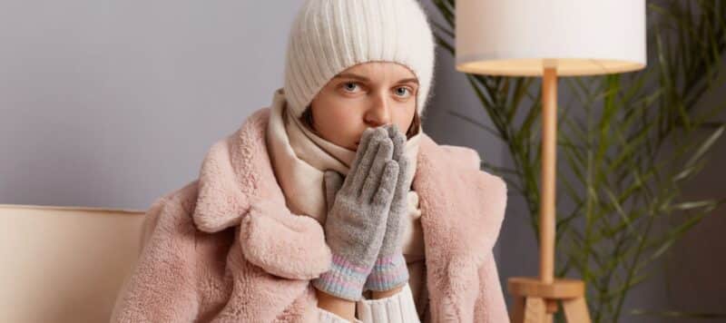 woman wearing winter clothes in door trying to get warm