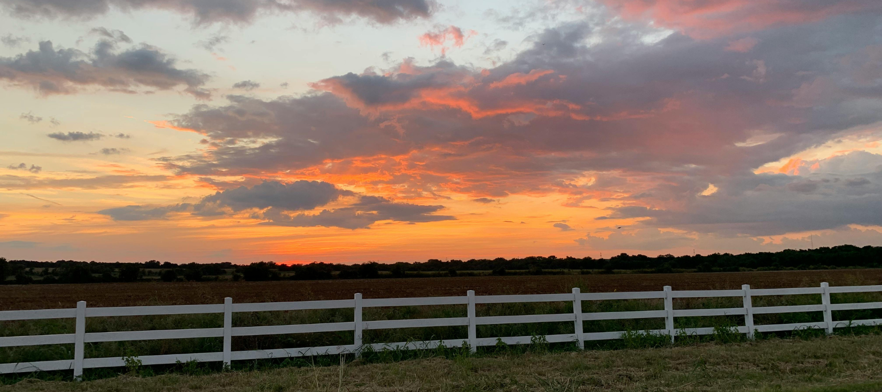 Beautiful Castroville TX sunset scene with open fields and fence, representing the service region of DrainWorks TX.