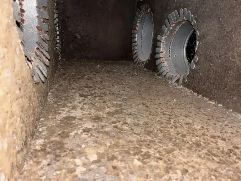 Dust and debris built up inside a supply duct trunk with round takeoffs